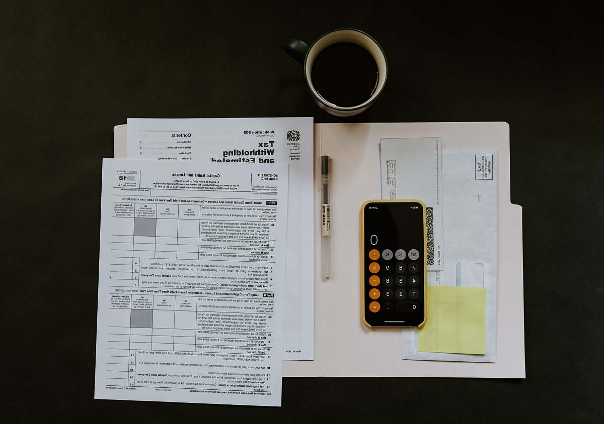 cell phone black Android smartphone near ballpoint pen, tax withholding certificate on top of white folder mobile phone